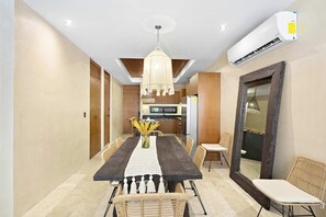 A modern dining area with a long table, chairs, a chandelier, and an air conditioning unit. - 5 stars Luxury Retreat  Rooftop Pool Whirlpool tub (tulum)