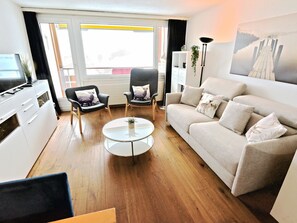 A modern living room with a sofa, two armchairs, a coffee table, and a TV. - Tgesa Sunnmatt 24 Appartement/Fewo, Bad, WC, 1 Schlafraum by Interhome (Savognin)