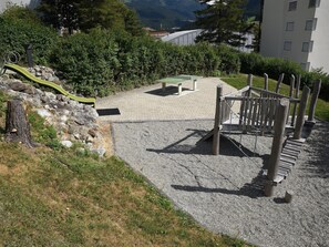 Ein Spielplatz mit Rutsche, Tischtennisplatte und einer Holz-Kletterkonstruktion.