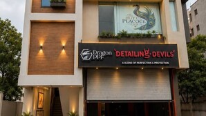 Een modern hotelgebouw met een bord waarop 'Hotel Peacock Inn' staat en een winkel voor 'Detailing Devils'.