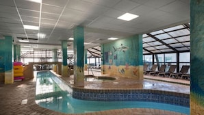 An indoor swimming pool with a tiled edge, a mural of marine life, and a sunroofed area with lounge chairs. - Compass Cove Beachfront Escape | Pool Access | Balcony | Hot Tub | Free Parking (Myrtle Beach)