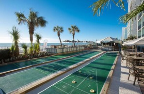 A pool table area with a view of the ocean, palm trees, and outdoor seating. - Compass Cove Beachfront Escape | Pool Access | Balcony | Hot Tub | Free Parking (Myrtle Beach)
