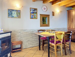 A dining area with a wooden table and chairs, a clock on the wall, and a map. - Baita Melissa by Interhome (Vercana)