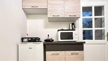 A compact kitchen with a refrigerator, microwave, and wooden cabinets.
