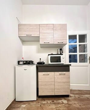Una cocina compacta con refrigerador, microondas y armarios de madera.