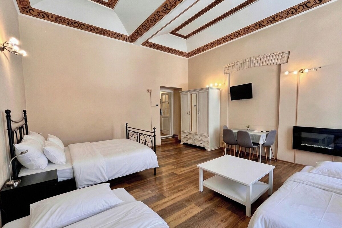 A hotel room with two beds, a desk, a TV, and a wardrobe.