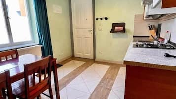 A kitchen with a dining table and chairs, a stove, and a door.