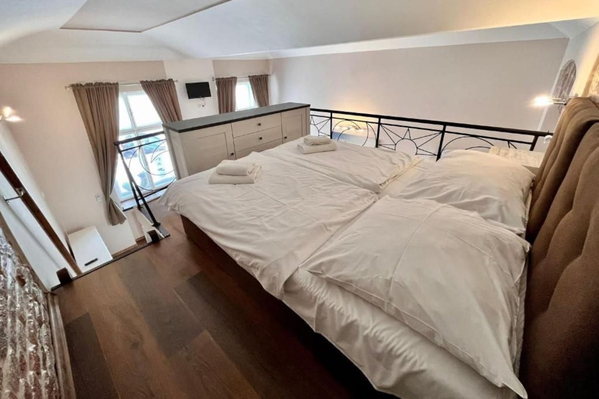 A bedroom with a bed, a dresser, a window with curtains, and a ceiling light.