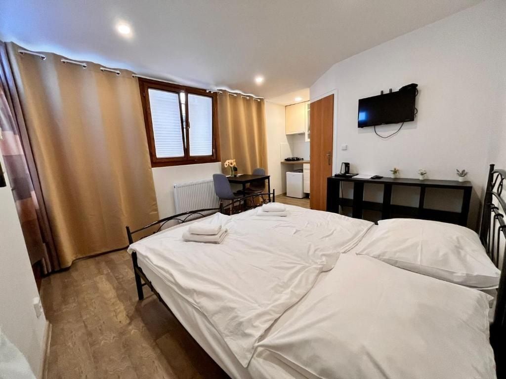 A bedroom with a bed, a desk, a chair, a television, and a radiator.