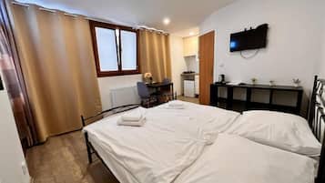 A bedroom with a bed, a desk, a chair, a television, and a radiator.