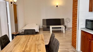 Un ambiente compatto con tavolo da pranzo, divano e angolo cottura.