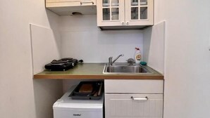 Una cucina compatta con frigorifero integrato, lavello e pensili.