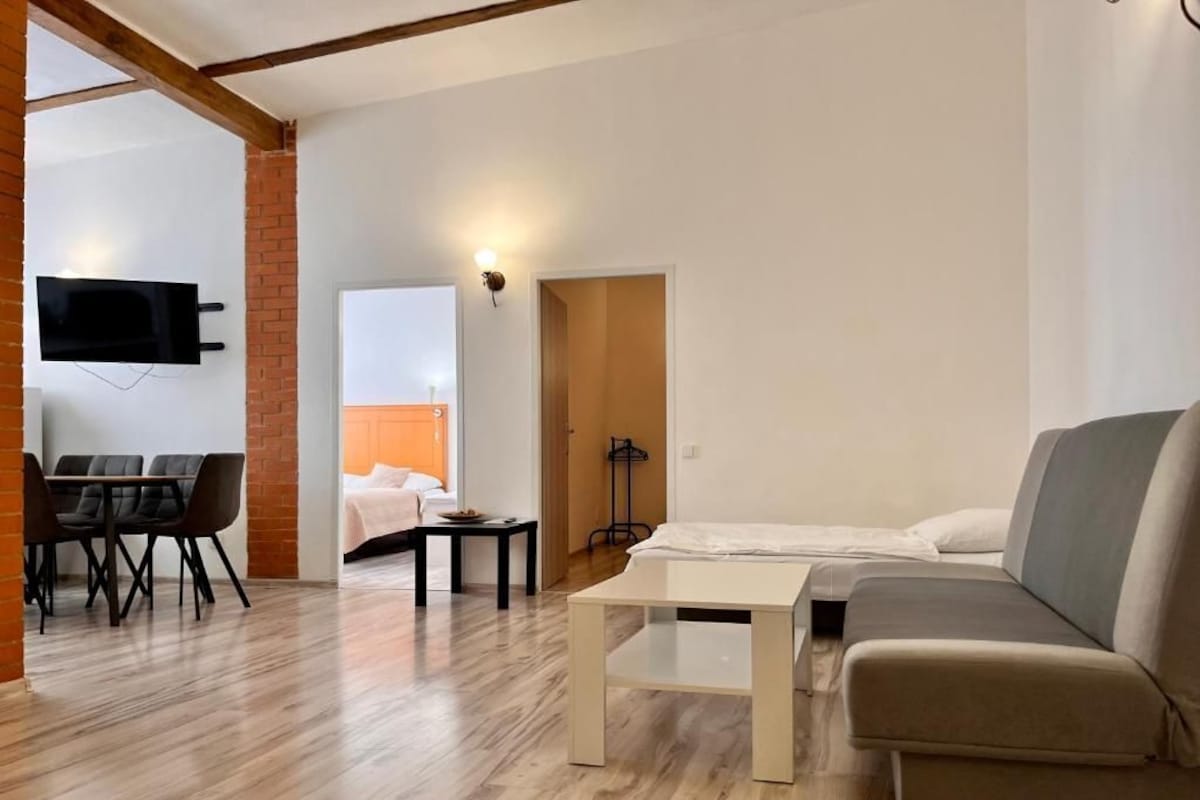 A modern living room with a sofa, a coffee table, and a dining area with chairs and a table.