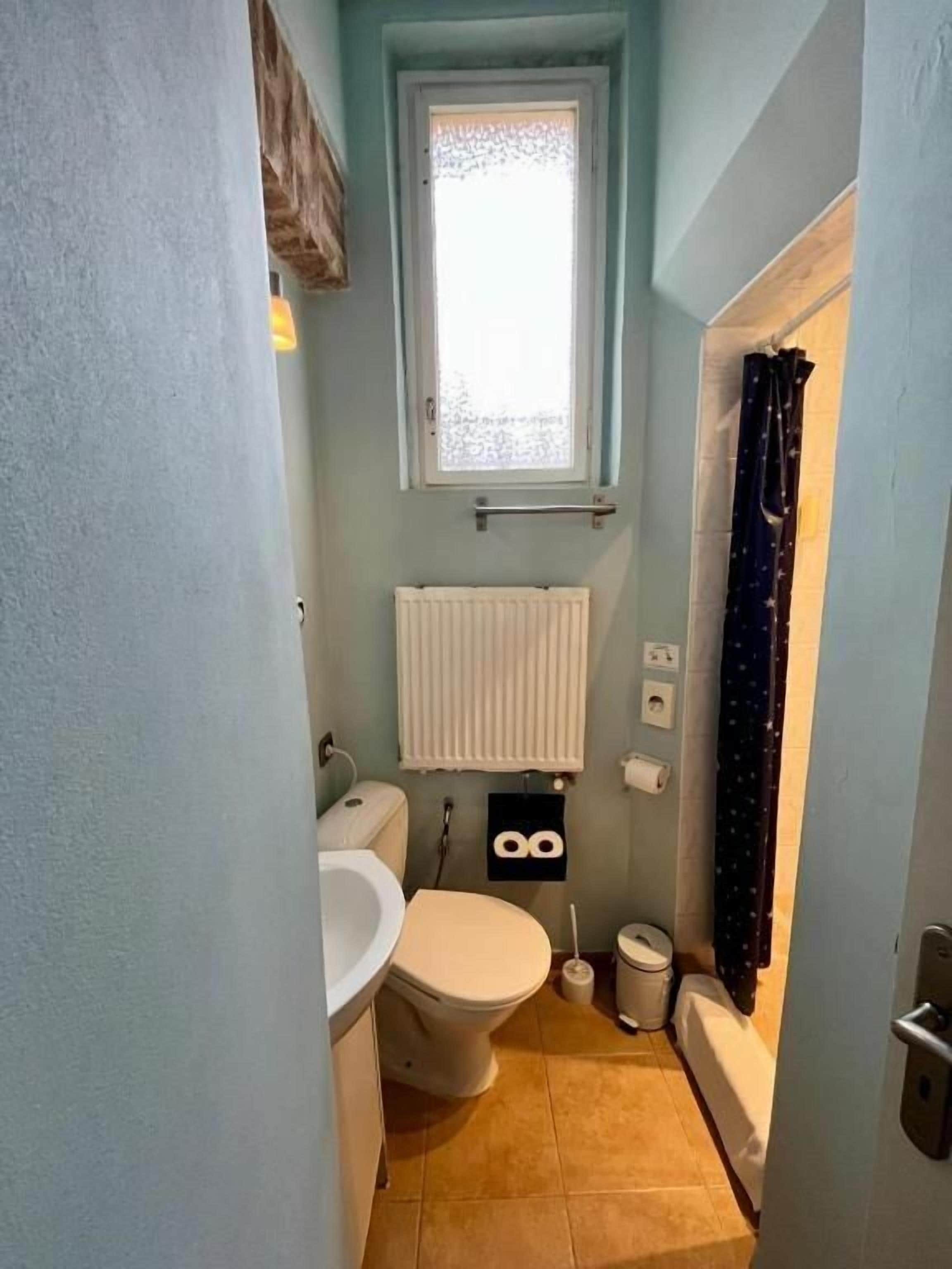 Un baño pequeño con inodoro, lavabo y ventana con cortina.