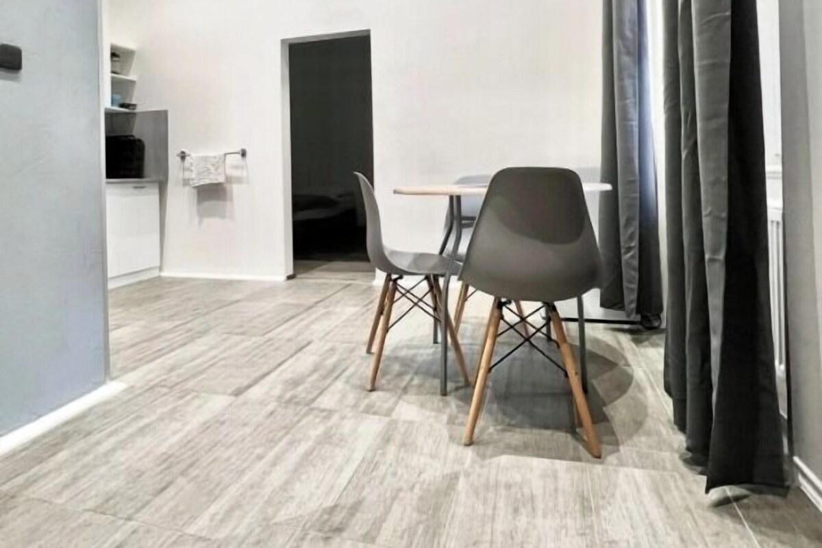A modern room with a dining area, a door, and a window with curtains.