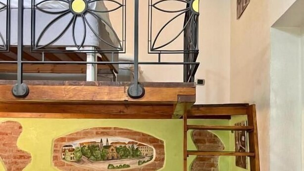 Una camera d'albergo con un letto, una scala, una parete decorativa e un soffitto in legno.