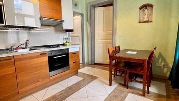 A compact kitchen with a dining area, featuring a built-in oven, a sink, and a dining table with chairs.