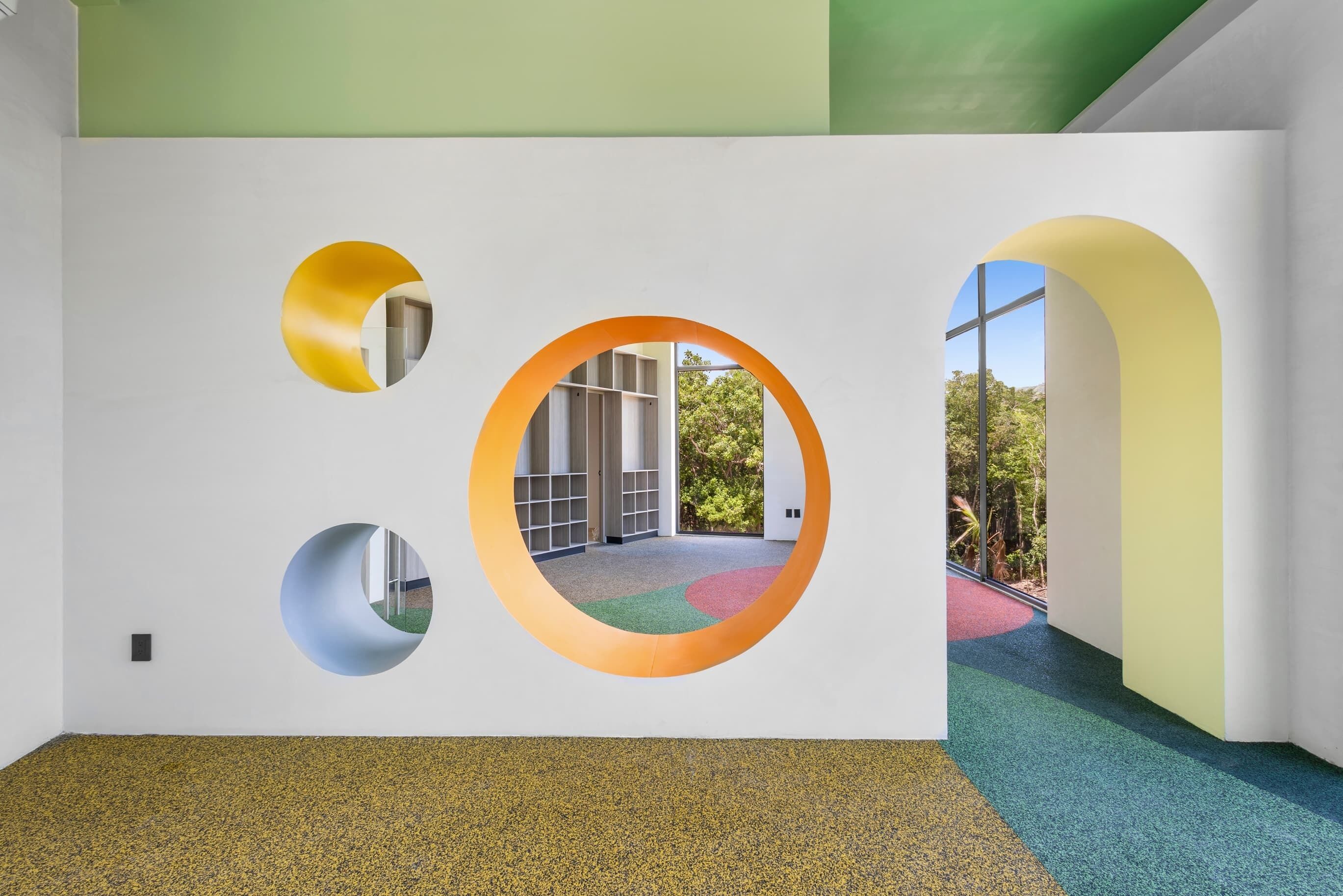 A hallway with white walls, circular cutouts, and a carpeted floor.