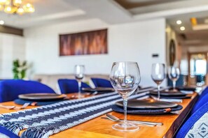 A dining table set with wine glasses, plates, and cutlery, with a patterned runner and blue upholstered chairs. - Urban Oasis (Nairobi)