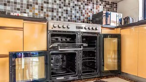 Una cocina con horno empotrado, microondas y cafetera sobre la encimera.