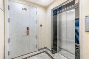 A hotel elevator with a metallic finish and a control panel on the wall. - Urban Oasis (Nairobi)