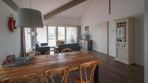 Un comedor con una mesa y sillas de madera, una lámpara grande y vistas al exterior por la ventana.