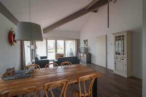 Ein Essbereich mit einem Holztisch und Stühlen, einer großen Lampe und Blick durch das Fenster.