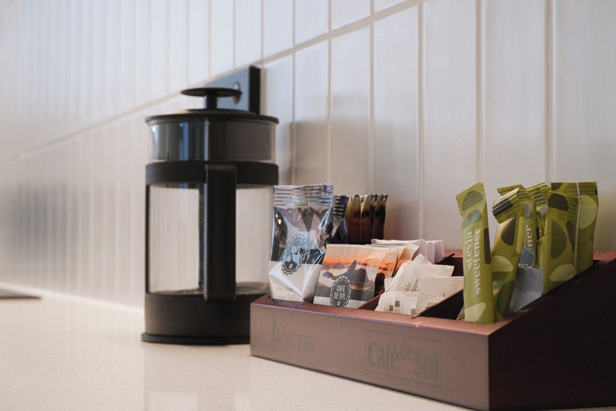 A coffee maker, a box of coffee pods, and a tray of snacks on a counter.
