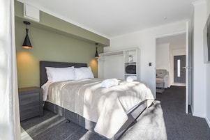 A neatly arranged bedroom with a bed, bedside tables, a wardrobe, and a mirror.