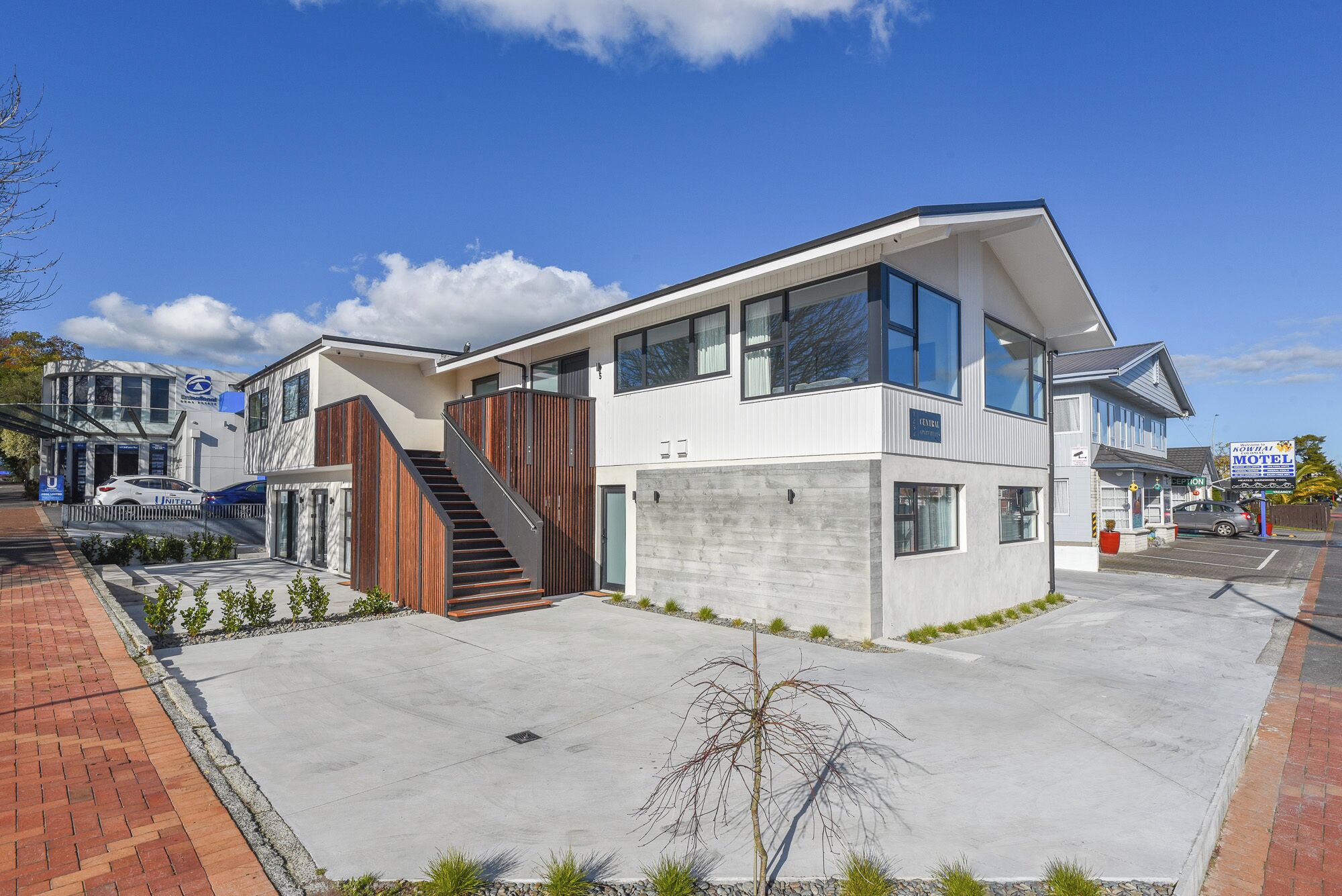 A modern two-story building with a central staircase, large windows, and a flat roof.