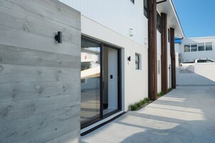 Een modern gebouw met een betonnen gevel, een glazen deuropening en een witte buitenmuur.