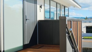 A modern building with large glass windows, a wooden deck, and a metal railing. - Central Apartments Rotorua (Rotorua)