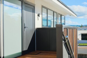 A modern building with large glass windows, a wooden deck, and a metal railing.