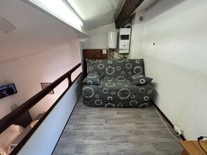 A bedroom with a bed, a heater, a wall-mounted TV, and a staircase. - Lovely 3-room semi-detached villa with mezzanine in Mont Saint-Martin, Cap d'Agde. (LE CAP D AGDE)