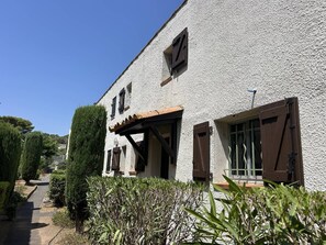 A building with a white exterior, a wooden pergola, and a window with a shutter. - Lovely 3-room semi-detached villa with mezzanine in Mont Saint-Martin, Cap d'Agde. (LE CAP D AGDE)