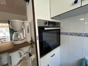 A kitchenette with a coffee maker, a kettle, an oven, and a microwave. - Lovely 3-room semi-detached villa with mezzanine in Mont Saint-Martin, Cap d'Agde. (LE CAP D AGDE)