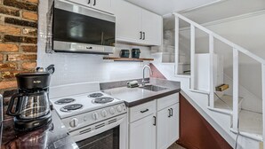 A kitchen with white cabinets, a stainless steel range hood, a built-in oven, and a coffee maker. - First Floor Retreat | Minutes to Stowe Mountain (Stowe)