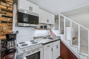 Eine Küche mit weißen Schränken, einer Edelstahl-Dunstabzugshaube, einem eingebauten Backofen und einer Kaffeemaschine.