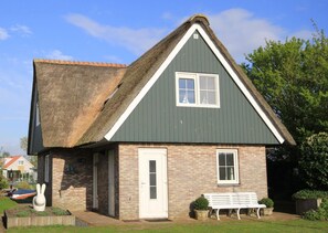 Una casa con techo inclinado, un pequeño porche y un banco blanco.