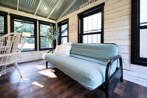 A room with a sofa, a chair, and large windows. - Secluded A-Frame on 10 Acres | At the Pines (Fennville)