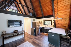 A modern kitchen with a large island, built-in appliances, and a high ceiling with exposed beams. - Secluded A-Frame on 10 Acres | At the Pines (Fennville)