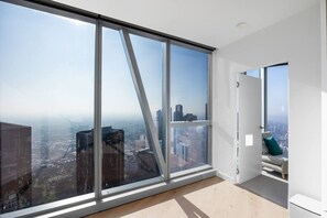 Ein Hotelzimmer in einem Hochhaus mit bodentiefen Fenstern und Blick auf die Stadt.