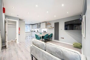 A modern kitchen with white cabinets, a dining area with green chairs, and a built-in bench. - Luxury 4BR House|Contractors • Corporate •Jacuzzi (London)