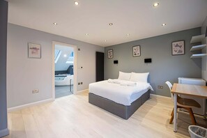 Quarto moderno com uma cama grande, uma mesa e uma cadeira.