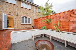 A brick house with a wooden fence, a bench, and a metal pot on the ground. - Luxury 4BR House|Contractors • Corporate •Jacuzzi (London)