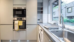 Une cuisine moderne dotée d’appareils électroménagers intégrés, d’une fenêtre et offrant une vue sur l’extérieur.