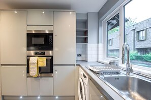 A modern kitchen with built-in appliances, a window, and a view of the outside. - Luxury 4BR House|Contractors • Corporate •Jacuzzi (London)