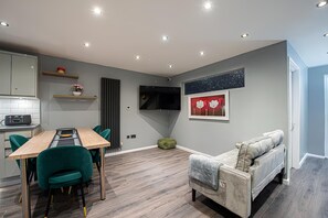 A modern living space with a dining area, a sofa, and a flat-screen TV mounted on the wall. - Luxury 4BR House|Contractors • Corporate •Jacuzzi (London)