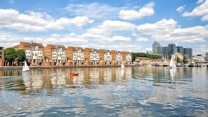Une promenade en bord de mer bordée d’immeubles en briques, une rivière paisible et, au loin, le profil de la ville.