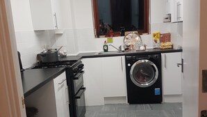 Une cuisine compacte équipée d’une cuisinière à gaz, d’un four, d’un lave-linge et d’une fenêtre située au-dessus de l’évier.